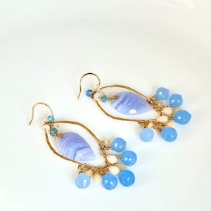 May include: A pair of gold dangle earrings with a light blue agate stone and blue and white beads.