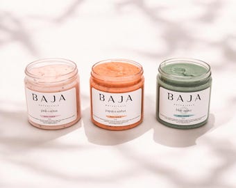 May include: Three glass jars of body scrub with white labels. The labels read "BAJA BOTANICALS" and the scent of each scrub: "pink cactus", "papaya sorbet", and "blue agave".