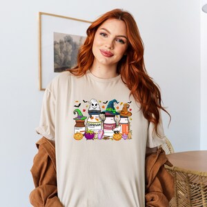 May include: A beige t-shirt with a Halloween-themed graphic featuring four bottles with witch hats and the text "Diprivan" and "Fentanyl".