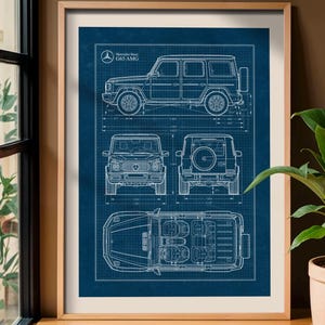 May include: Framed blueprint of a Mercedes-Benz G63 AMG SUV, featuring side, front, rear, and top views in white lines on a blue background. The print includes the Mercedes-Benz logo and model name. The frame is a light brown color.