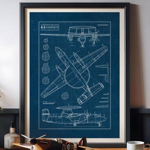 May include: Framed blueprint of a Northrop Grumman E-2 Hawkeye aircraft in white on a blue background. A model airplane sits in front of the framed blueprint. The model airplane is brown, black, and white.