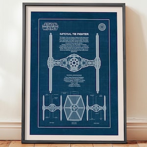 May include: Framed blueprint art print of an Imperial TIE Fighter from Star Wars. The blueprint is white on a blue background, with detailed technical specifications and the Star Wars logo at the top. The print is in a black frame.