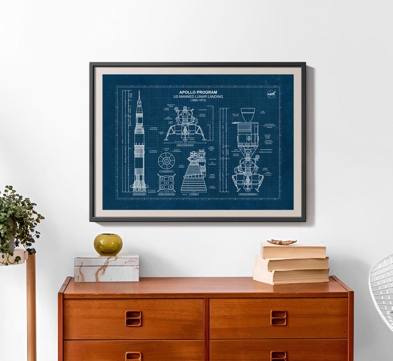 K&ouml;nnte beinhalten: Gerahmter Kunstdruck mit einem Bauplan des Apollo-Programms US Manned Lunar Landing (1960-1973). Der Druck zeigt technische Zeichnungen der Saturn V-Rakete und der Mondlandef&auml;hre auf dunkelblauem Hintergrund. Der Druck ist in einem schwarzen Rahmen.