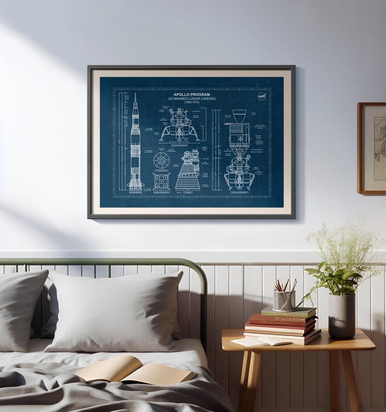 K&ouml;nnte beinhalten: Gerahmter Bauplan des Apollo-Programms US Manned Lunar Landing mit detaillierten Schemata der Saturn V-Rakete und der Mondlandef&auml;hre. Der Druck ist wei&szlig; auf dunkelblauem Hintergrund, in einem schwarzen Rahmen.