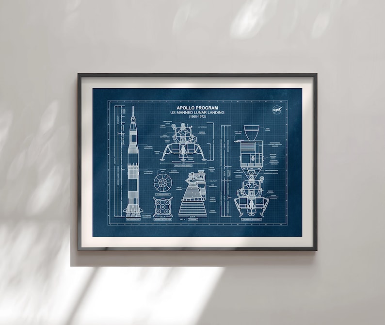 K&ouml;nnte beinhalten: Gerahmter Kunstdruck mit einem Bauplan des Apollo-Programms US Manned Lunar Landing (1960-1972). Der Druck zeigt detaillierte technische Zeichnungen der Saturn V-Rakete und der Mondlandef&auml;hre auf dunkelblauem Hintergrund. Der Druck ist in einem schwarzen Rahmen.