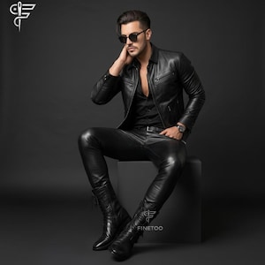May include: A black leather jacket with a front zipper and chest pockets, paired with matching black leather trousers and black lace-up leather boots. The outfit is worn with a black button-down shirt, dark sunglasses, and a wristwatch.
