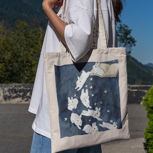 Colorful Canvas Tote Bag Featuring Magical Bunnies, frolicking from a book. Perfect for carrying library books or daily essentials, canvas and durable.