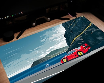 Può includere: Un tappetino per mouse con un'illustrazione di un'auto sportiva rossa su una strada costiera. Il design presenta un'auto rossa con ruote gialle su una strada vicino al mare, con una scogliera rocciosa e cielo blu.