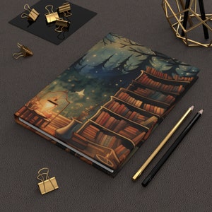 May include: A dark blue and brown journal with a whimsical illustration of a bookshelf filled with books, a lantern, and a starry night sky. The journal has a white border around the edges.