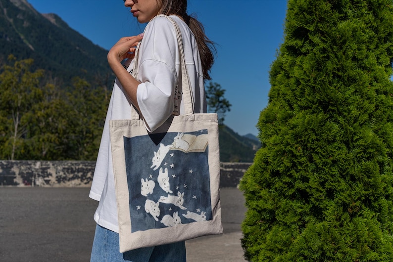 Colorful Canvas Tote Bag Featuring Magical Bunnies, frolicking from a book. Perfect for carrying library books or daily essentials, canvas and durable.
