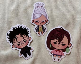 Puede incluir: Tres pegatinas de dibujos animados con personajes estilizados. Una pegatina representa a una mujer con gafas y un moño, otra a un joven con gafas redondas y la tercera a una mujer con pelo corto y pendientes. Todos están en estilo chibi.