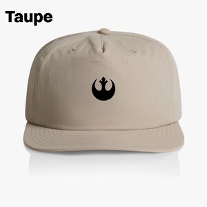May include: A beige baseball cap with a black Rebel Alliance symbol on the front. The cap is labeled "Taupe".
