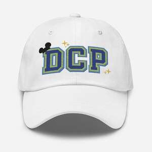 Puede incluir: Gorra de béisbol blanca con un logotipo bordado en azul y amarillo que dice "DCP" con una silueta de Mickey Mouse negra sobre el texto.