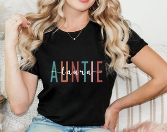 May include: A black t-shirt with the text "AUNTIE Laura" in colorful, vertical stripes.