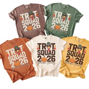 May include: Five short-sleeved t-shirts in brown, green, orange, cream, and yellow. Each features a graphic of a turkey wearing a green beanie and sunglasses, with the text TROT SQUAD 2026, a pumpkin, autumn leaves, and the script text Johnson Family.
