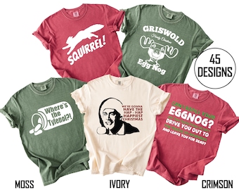 May include: Five short-sleeved crew neck t-shirts in moss green, ivory, and crimson red. The shirts feature various white and red graphic prints with text including SQUIRREL!, GRISWOLD Family Christmas Egg Nog, Where's the Tylenol?!, and movie quotes.