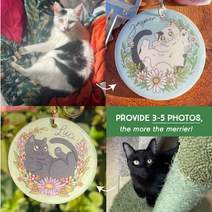 May include: Two cat keychains with floral designs. The keychain on the left has a black cat with the name "Luci" on it. The keychain on the right has a white cat with the name "Jasper" on it.  The keychains are on a green background.