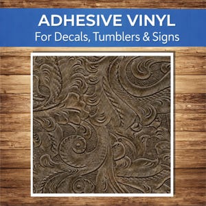 May include: Adhesive vinyl with a brown embossed floral pattern, suitable for decals, tumblers, and signs. The text "ADHESIVE VINYL" is displayed above the image, with "For Decals, Tumblers & Signs" below it. The background is a wooden texture.