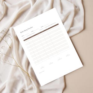 Könnte beinhalten: Ein weißes Blatt Papier mit der Überschrift Baby Sleep Tracker, einem dunkelbraunen Kopfbereich und Rasterlinien zur Erfassung von Datum, Uhrzeit und Schlafdauer. Das Dokument enthält Abschnitte für Notizen und die gesamte Schlafzeit.