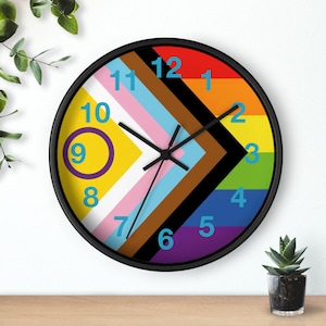 May include: A black framed clock with a rainbow and brown striped design. The clock face has a white background with black hands and blue numbers.