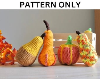 Puede incluir: Cuatro decoraciones de otoño tejidas a crochet: una pera, una calabaza, una calabaza y una calabaza. La pera es marrón y amarilla, la calabaza es naranja y amarilla, la calabaza es naranja y amarilla y la calabaza es verde, naranja y amarilla.