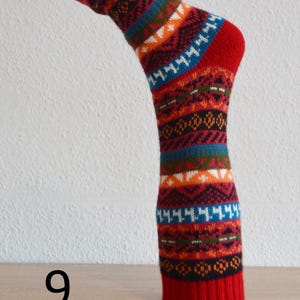 May include: A single red sock with a colourful geometric pattern. The sock features bands of blue, orange, white, and black designs. The number "9" is visible in the lower left corner.