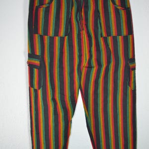 Könnte beinhalten: Gestreifte Hose mit Kordelzugbund und Taschen. Die Hose ist schwarz mit roten, grünen und gelben Streifen.