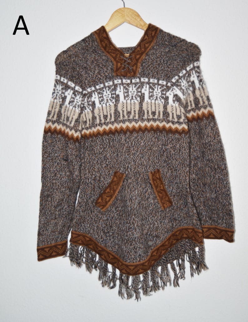 May include: A brown and white knit poncho with a hood and a front pocket. The poncho features a geometric pattern and fringe along the bottom. The design includes a pattern of llamas.
