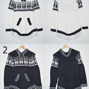 May include: Two hooded ponchos, one white and one charcoal gray, displayed on wooden hangers. Both feature a decorative pattern of figures and geometric shapes in black and white, with fringe along the bottom and pocket details.
