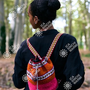 May include: A colorful woven backpack with a drawstring closure. The bag features a vibrant mix of orange, pink, and white patterns, with a decorative strap. The backpack is worn over a black shirt.
