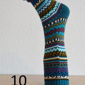 May include: A teal sock with a geometric pattern in white, red, and gold. The sock is displayed on a wooden surface with the number 10 in black.