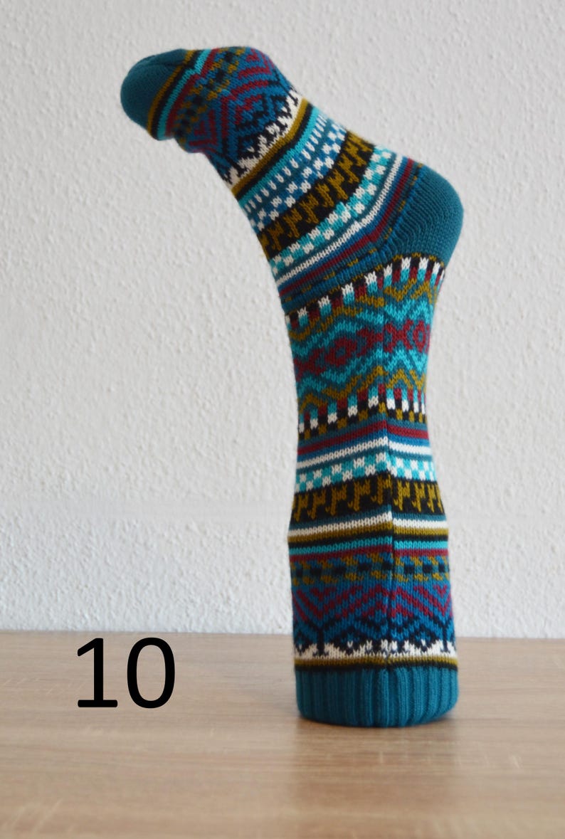 May include: A teal sock with a geometric pattern in white, red, and gold. The sock is displayed on a wooden surface with the number 10 in black.