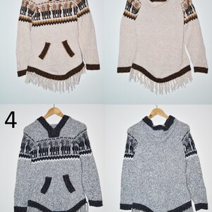 May include: Two hooded ponchos, one beige and one gray, with intricate patterns and fringe detailing. The beige poncho features brown accents and a llama design, while the gray poncho has black accents and a similar pattern. Both are displayed on wooden hangers.