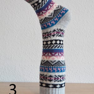 May include: A grey sock with a colourful geometric pattern, displayed on a form. The design includes blue, purple, pink, and black shapes. The number "3" is visible in the lower left corner.