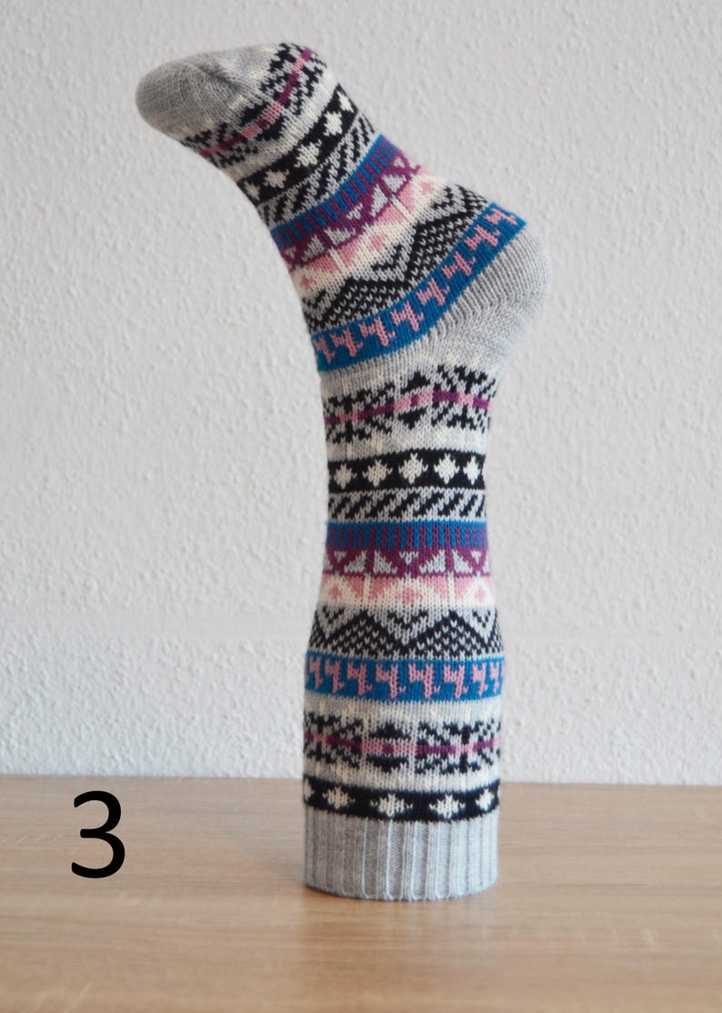 May include: A grey sock with a colourful geometric pattern, displayed on a form. The design includes blue, purple, pink, and black shapes. The number "3" is visible in the lower left corner.