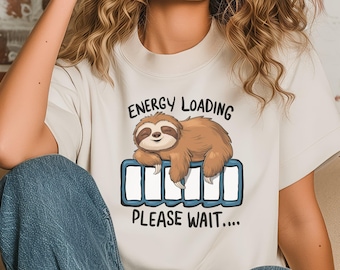 Peut inclure: Un t-shirt blanc avec un graphique d'un paresseux dormant sur une barre de charge de batterie de téléphone. Le texte sur le t-shirt est "Energy Loading Please Wait..."