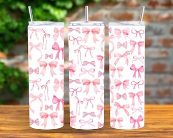 Peut inclure: Trois gobelets en acier inoxydable avec des motifs de nœuds roses en aquarelle. Les gobelets sont blancs avec un motif de nœuds roses et blancs.