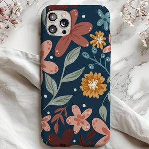 May include: A blue phone case with a floral pattern. The flowers are in shades of pink, orange, and brown. The case has a cutout for the camera lens.