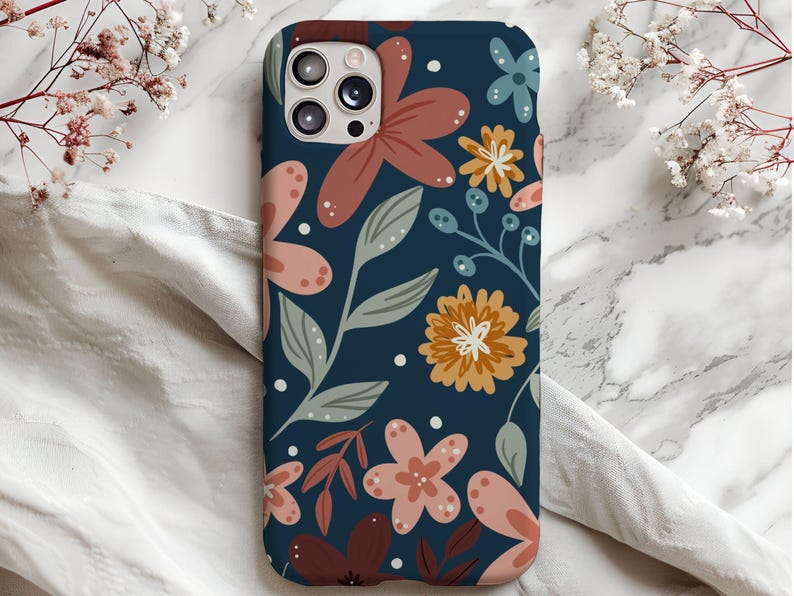 May include: A blue phone case with a floral pattern. The flowers are in shades of pink, orange, and brown. The case has a cutout for the camera lens.