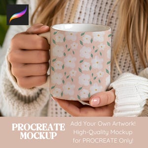 May include: A ceramic mug with a floral pattern of white flowers and green leaves on a light pink background. The mug is held by a person wearing a white sweater. The mug has the text "PROCREATE MOCKUP" and "Add Your Own Artwork! High-Quality Mockup for PROCREATE Only!"