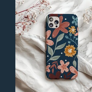 May include: A navy blue phone case with a floral pattern featuring pink, red, and yellow flowers. The case has a camera cutout and a white background.