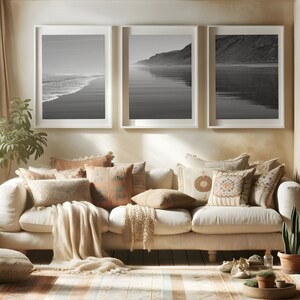 Puede incluir: Un sof&aacute; blanco con una manta de lana beige y varios cojines estampados. Tres fotograf&iacute;as en blanco y negro enmarcadas de una escena de playa cuelgan en la pared detr&aacute;s del sof&aacute;.