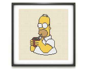 May include: Cross-stitch art of Homer Simpson drinking from a cup with a straw. The artwork features a yellow-skinned character with a white shirt and black framed art. The background is a light beige color.