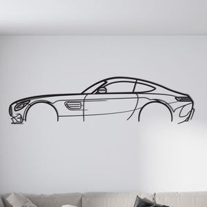 Könnte beinhalten: Schwarze Metall-Wandkunst, die eine elegante Sportwagen-Umrisslinie darstellt. Das Kunstwerk ist an einer weißen Wand über einem hellfarbigen Ecksofa angebracht. Der Raum hat ein modernes Design mit einem Holztisch und einem gemusterten Teppich.