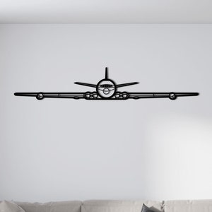 Op de afbeelding: Zwarte metalen vliegtuig wandkunst. Het kunstwerk toont een vooraanzicht van een vliegtuig, met vleugels, romp en motoren. Het minimalistische ontwerp is geschikt voor diverse interieurstijlen en voegt een vleugje luchtvaart toe.