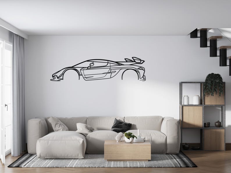 Puede incluir: Arte mural de metal negro que representa el contorno de un elegante coche deportivo. La obra de arte est&aacute; montada en una pared blanca sobre un sof&aacute; seccional de color claro. El dise&ntilde;o del coche incluye un aler&oacute;n y l&iacute;neas detalladas.