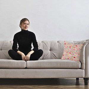 woman on sofa with pillow with design of hearts and flowers