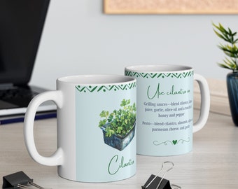 May include: Two white ceramic mugs with a green and white geometric pattern. One mug features a drawing of coriander and the text "Cilantro" and "Use cilantro in". The text below the drawing reads "Grilling sauces - blend coriander, lime juice, garlic, olive oil and a touch of honey and pepper. Pesto - blend coriander, almonds, and parmesan cheese, and garlic."