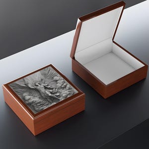 May include: Two wooden boxes, one open and one closed, with a detailed relief carving on the closed box lid. The carving depicts a figure with wings, set against a cloudy background. The boxes have a glossy finish.