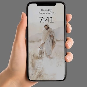 May include: A black smartphone displaying a religious image of a figure with a lamb. The screen shows the date "Thursday, December 25" and time "7:41". The phone is held in a hand against a gray background.